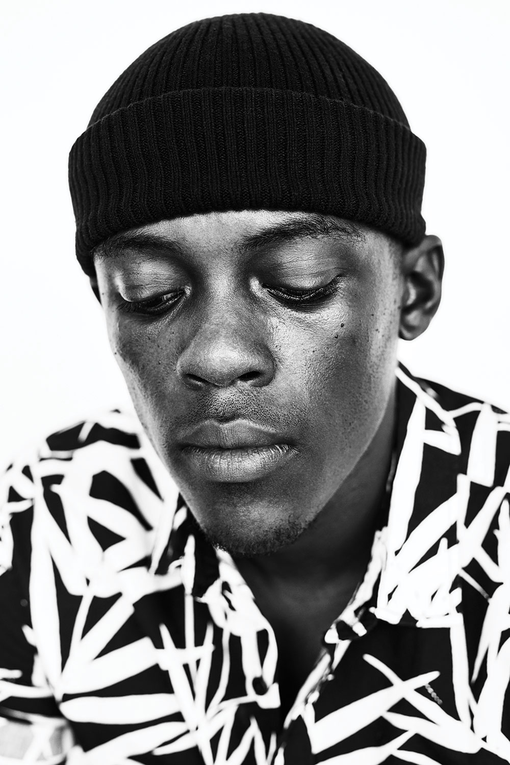 Black and white close-up portrait in a knit cap and patterned shirt
