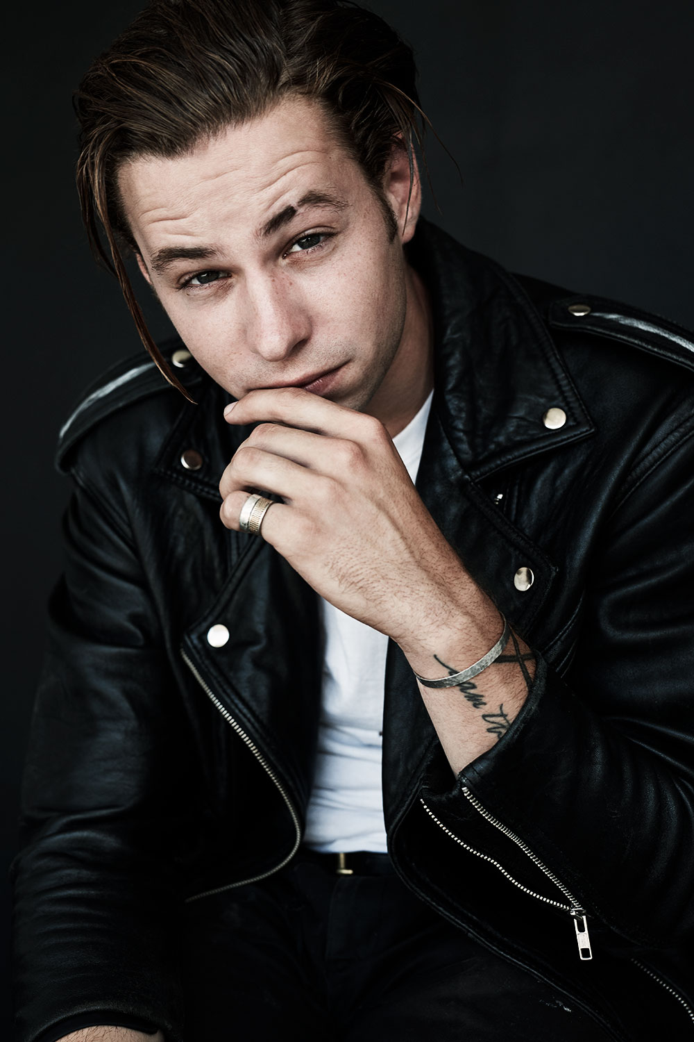 Portrait in a leather jacket with a hand near the face