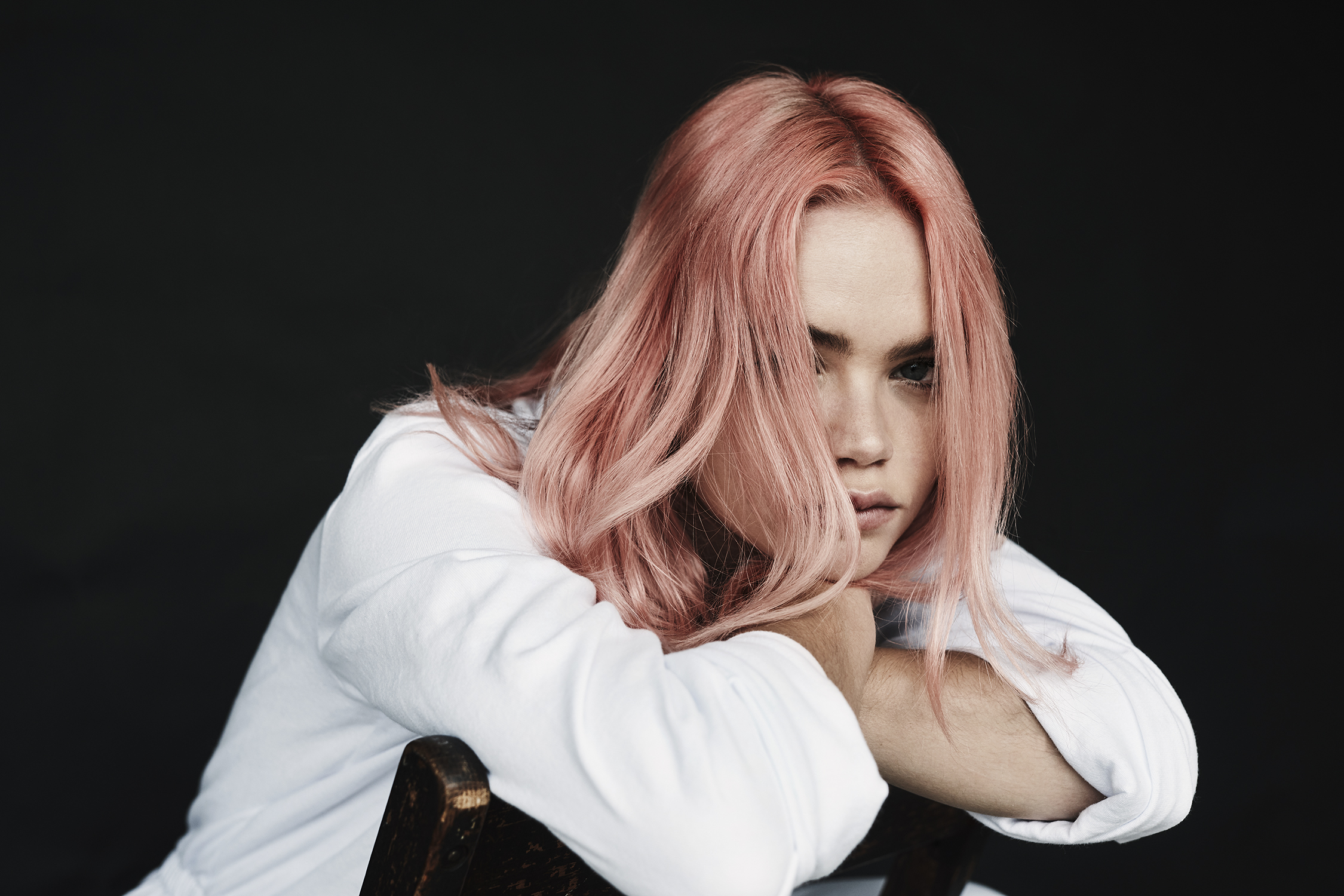 Horizontal portrait with pink hair resting on folded arms